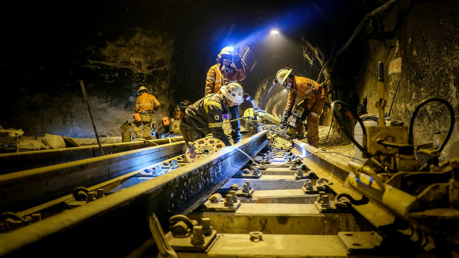 Crew in hi-vis working on underground rail track under head torches, the kind of operation that has to be crewed around the clock