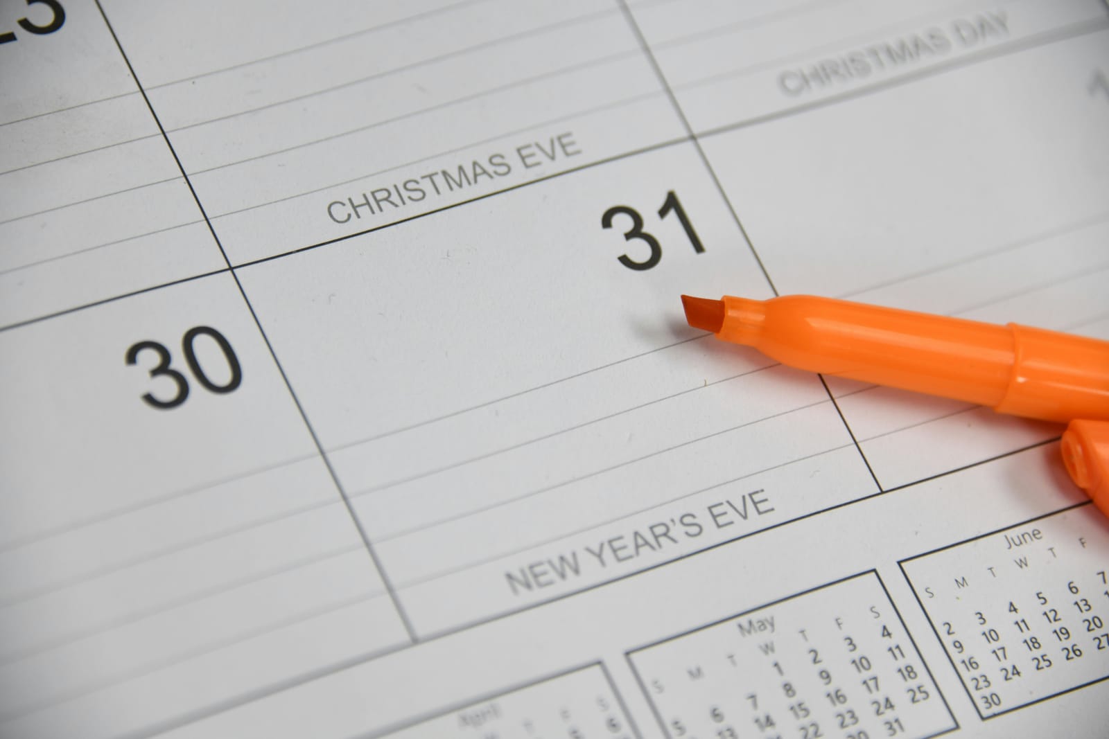 A printed planner page marking Christmas Eve, Christmas Day and New Year's Eve, with an orange highlighter resting on the 31st