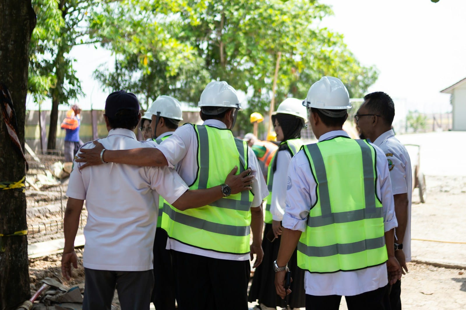 Field crew in hard hats and hi-vis huddled for a briefing before mobilising to site