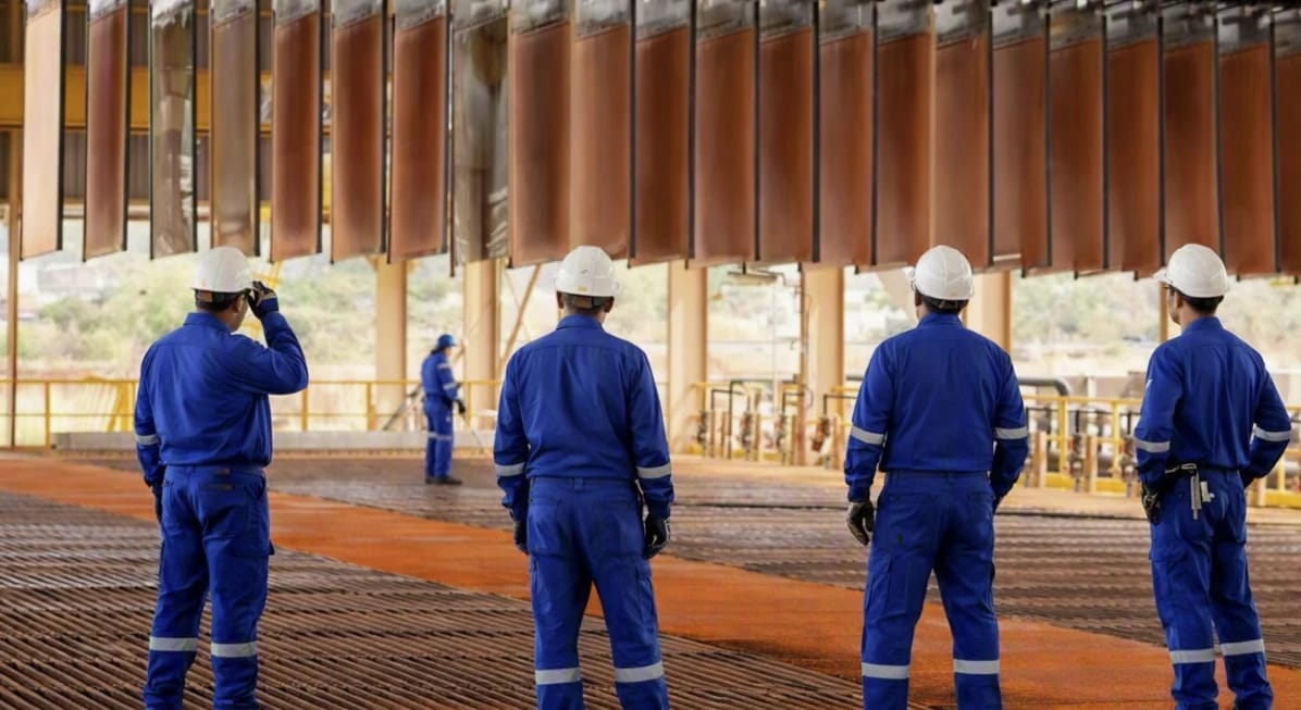 Subcontractors and direct employees in identical workwear standing together on the plant floor, one crew on one roster