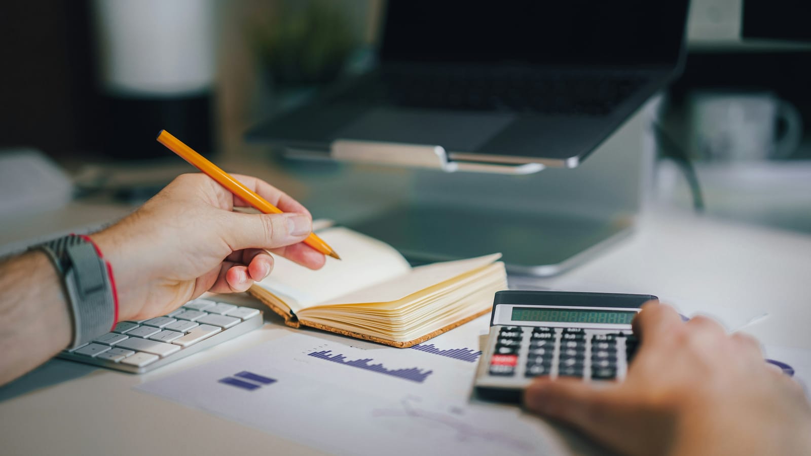 Working through the numbers with a calculator, notebook and charts before a commercial decision